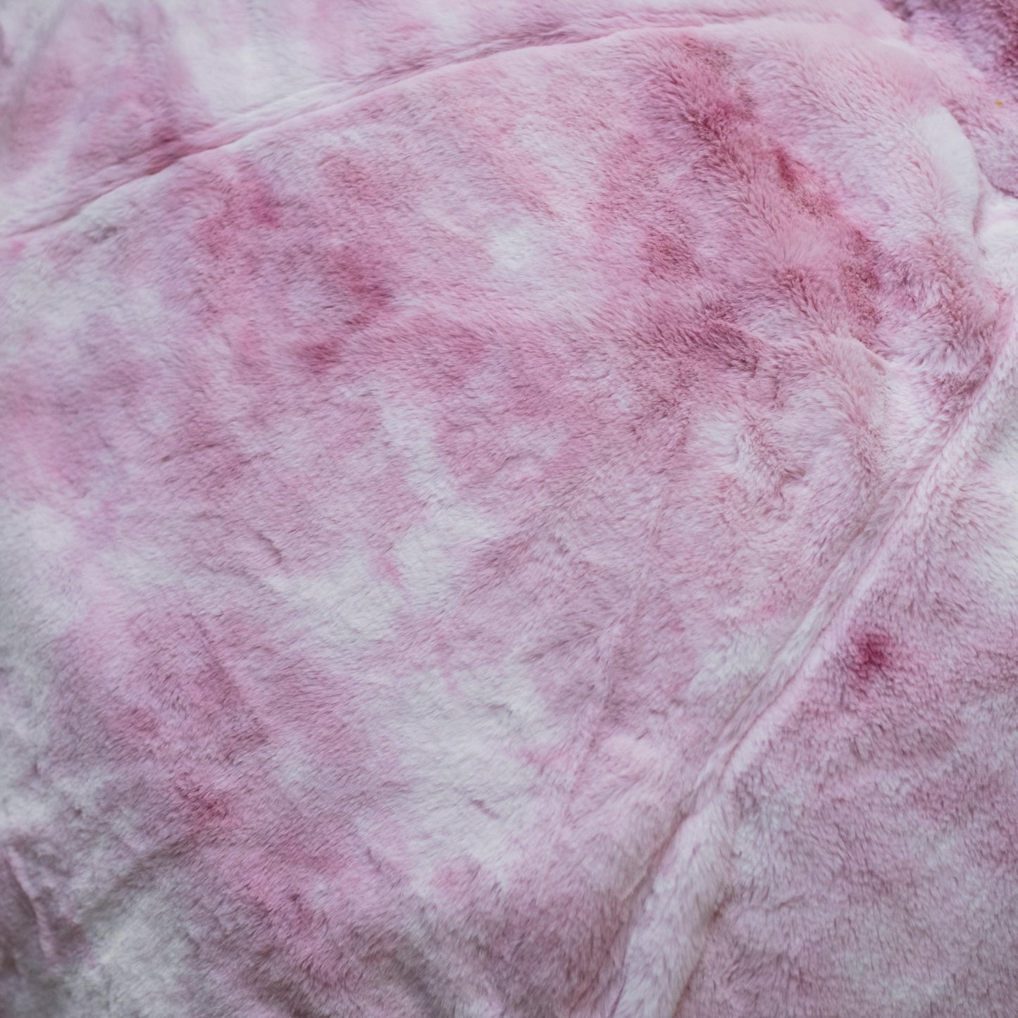 Marble pink plush fur fabric close-up with visible texture and seam lines