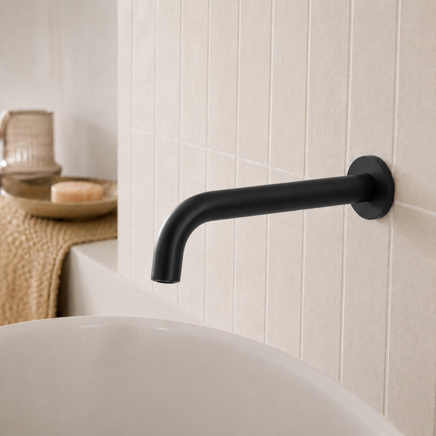 Wall-mounted matte black spout with curved profile and round backplate for sink