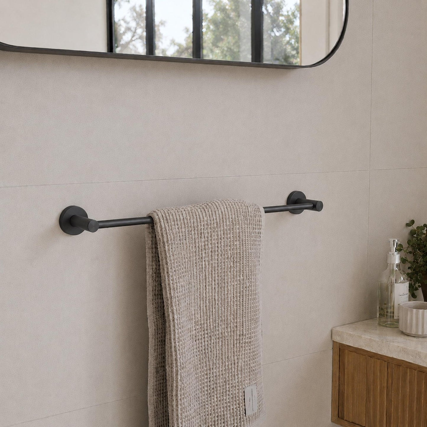 Wall-mounted matt black single towel rail with a beige towel draped over bar.