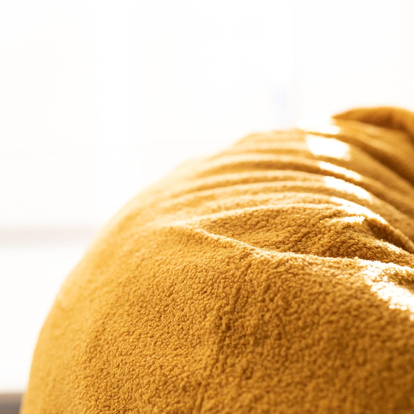 Mustard boucle bean bag close-up, textured fabric surface
