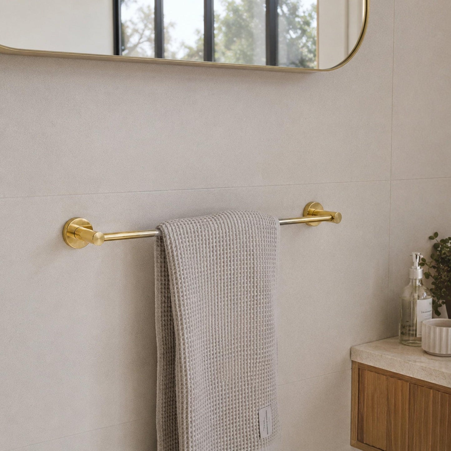 Polished gold single towel rail with textured gray towel draped over the bar