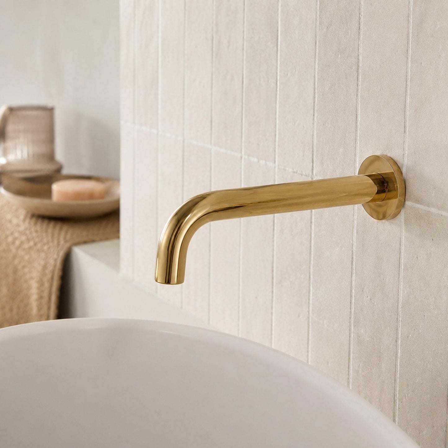 Polished gold wall-mount faucet spout with smooth curved arm