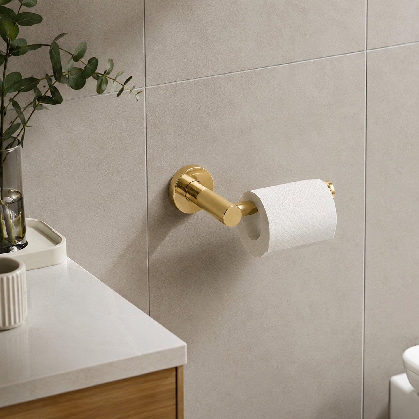 Polished gold wall-mounted toilet roll holder holding a paper roll