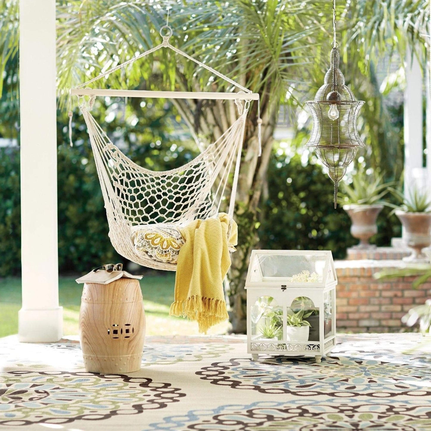 Natural macrame hanging hammock chair with seat cushion and fringe on patio
