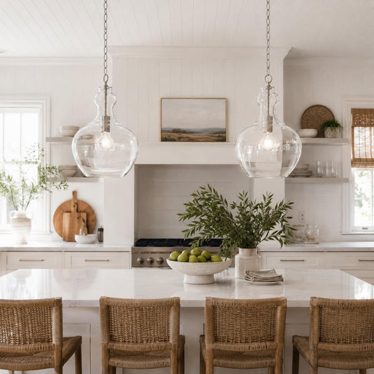 Pair of chrome hanging pendants with clear glass shades over kitchen island