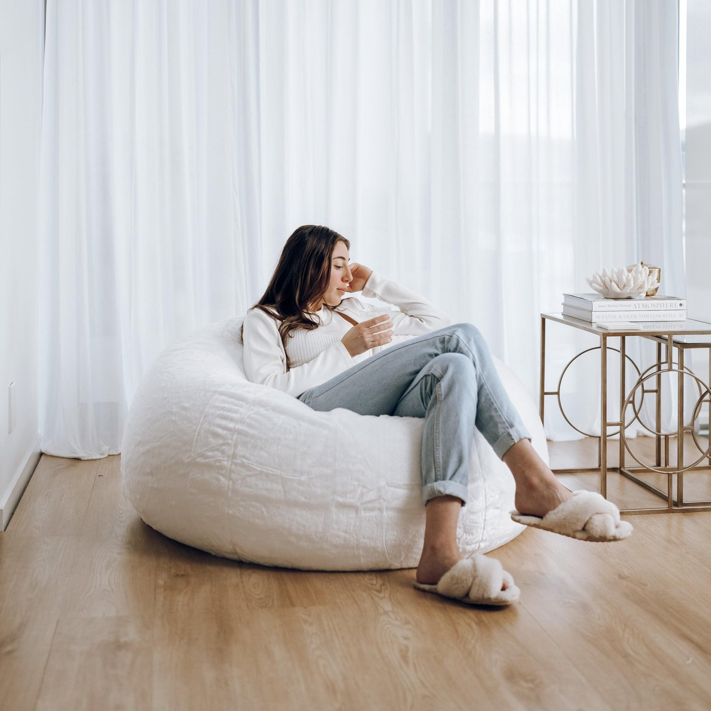 White plush bean bag with person lounging, cloud shape and seams visible