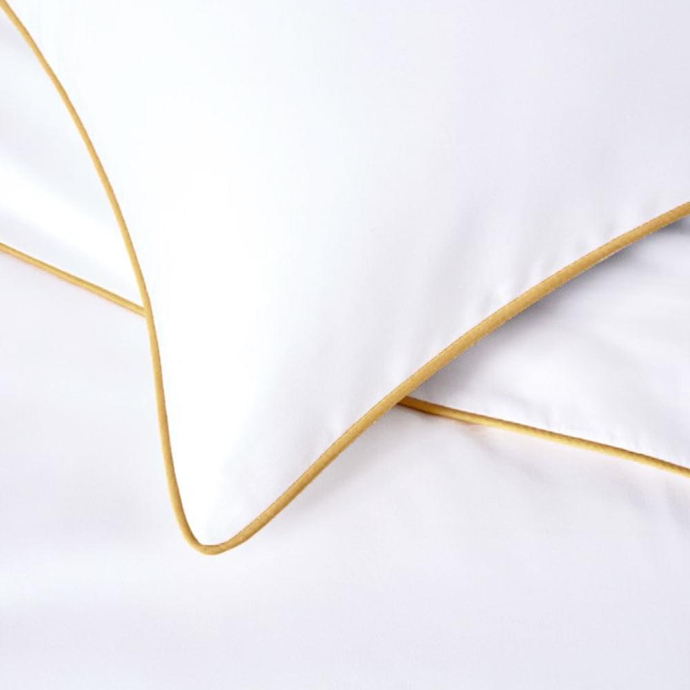 Close-up of white quilt cover edge with gold piping seam
