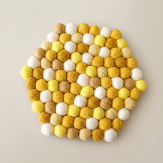 Round wool felt trivet with honey yellow, tan, and white felt ball pattern