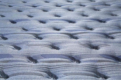 Close-up of blue quilted mattress fabric with ridged stitched wave pattern
