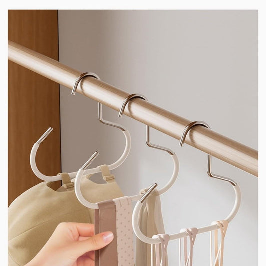 White hanging hooks with U-shaped grips on a light wood wardrobe rod