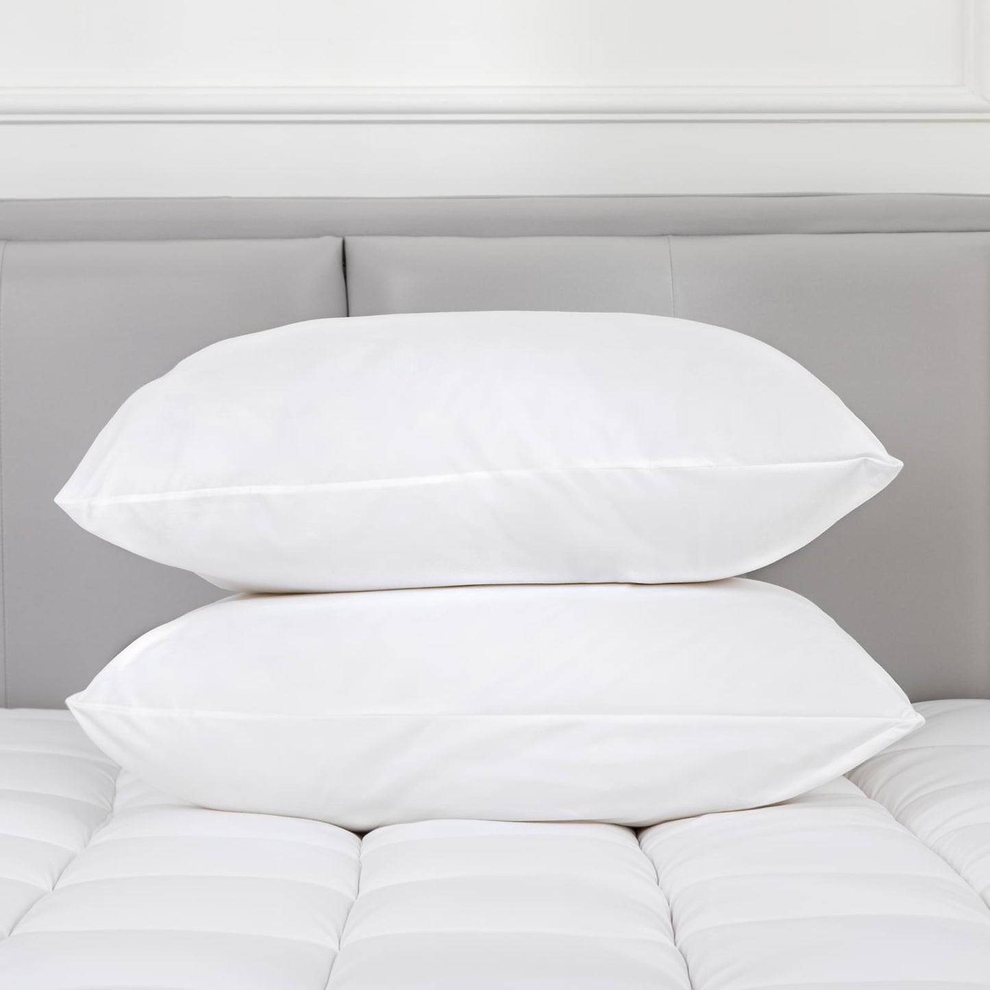 White pillows stacked on bed, cotton covers with plush poly-filled cushions