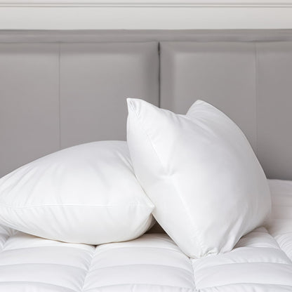 White cotton-covered pillows on bed, plush poly-filled cushions