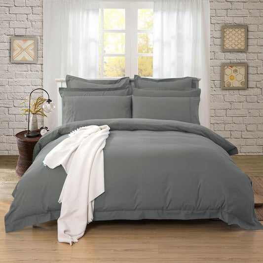 Charcoal quilt and duvet cover set with matching pillow shams, neatly made on a bed