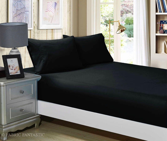 King fitted sheet and pillowcases set in black, smooth wrinkle-free fabric on bed