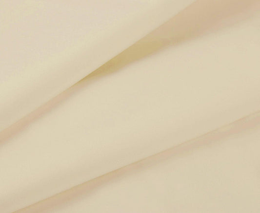 Beige fitted sheet fabric close-up with smooth surface and stitched edge