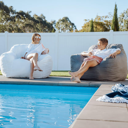 Two outdoor bean bag chairs: charcoal grey and white with rounded cushions