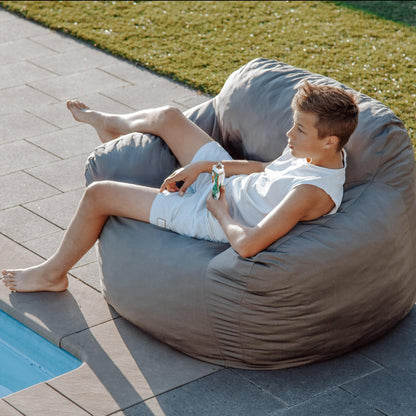 Charcoal grey outdoor bean bag chair, shown being lounged on