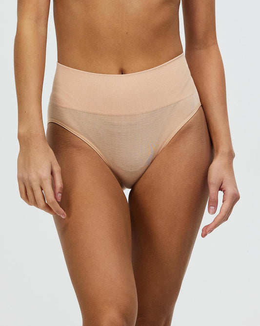 Beige high-cut brief underwear with smooth waistband, model standing side view