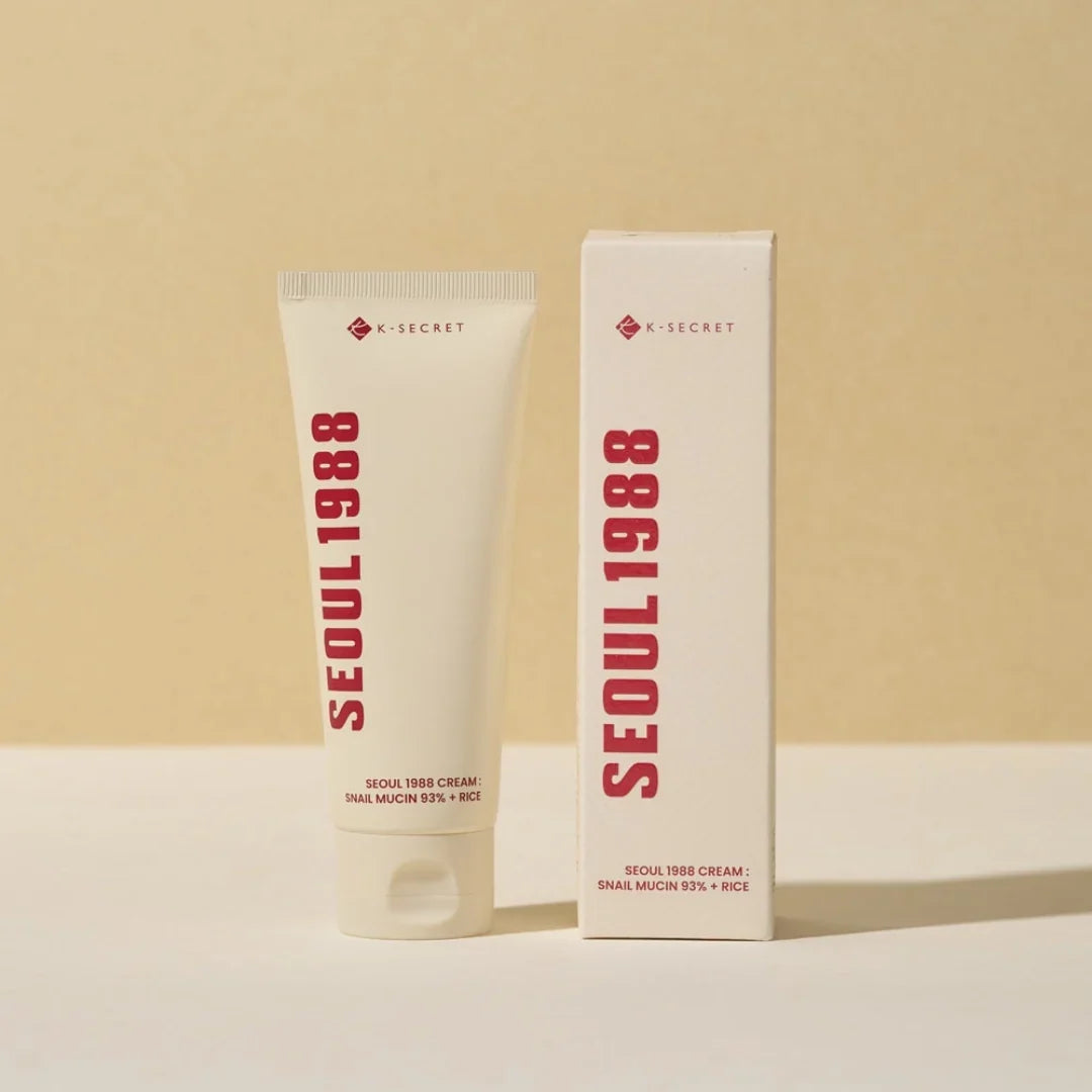 Two K-SECRET cream tubes standing side by side, cream-colored facial moisturizer