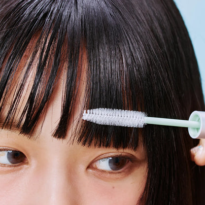 Close-up of mint brush comb applying hair sebum mascara to blunt bangs