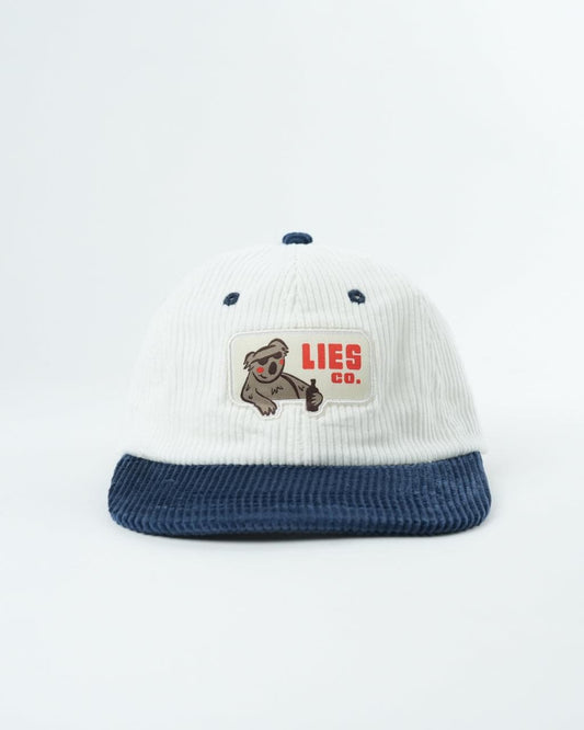 White knit cap with navy brim, dotted studs, and LIES CO. koala patch