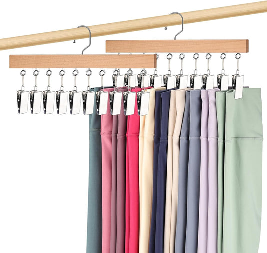 Wooden legging hanger with metal clips holding multiple leggings in assorted colors