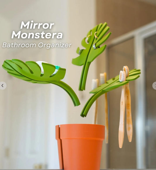 Bathroom mirror organizer with green monstera leaf holders and orange vase