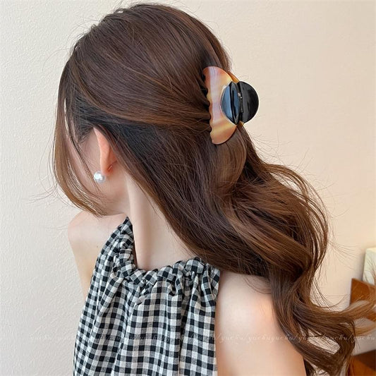 Hair claw clip on dark brown ponytail, oval wood-grain acetate patchwork in back view.