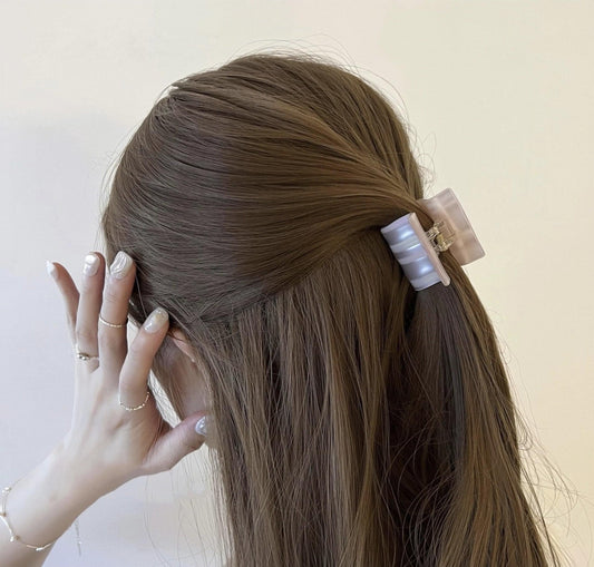 Small pink striped square claw hair clip on dark hair