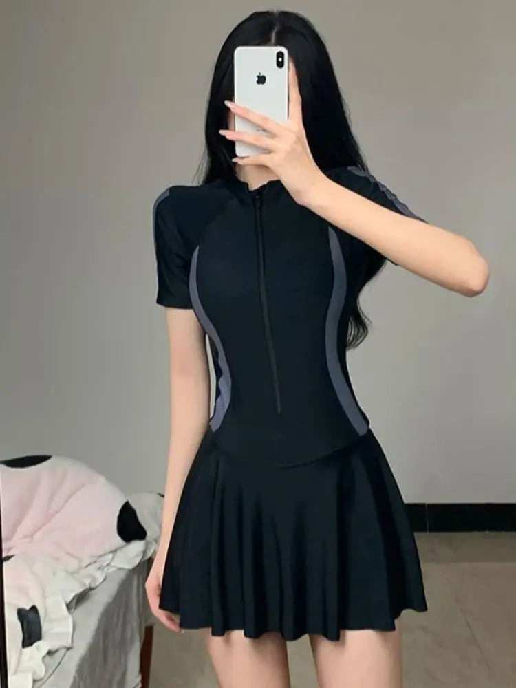 Dark skirted one-piece swimsuit with short sleeves, front zipper, and white side stripes