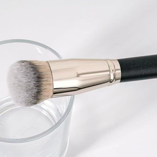 Foundation brush head with soft gray bristles in silver ferrule over clear jar