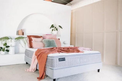 Light gray mattress with folded bedding and orange blanket on top