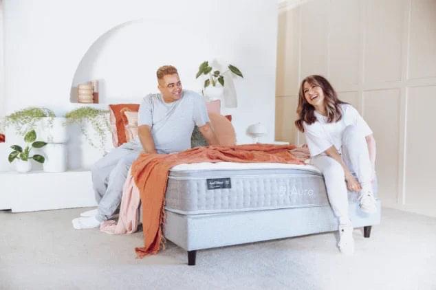 Light gray mattress with orange throw blanket draped across the top