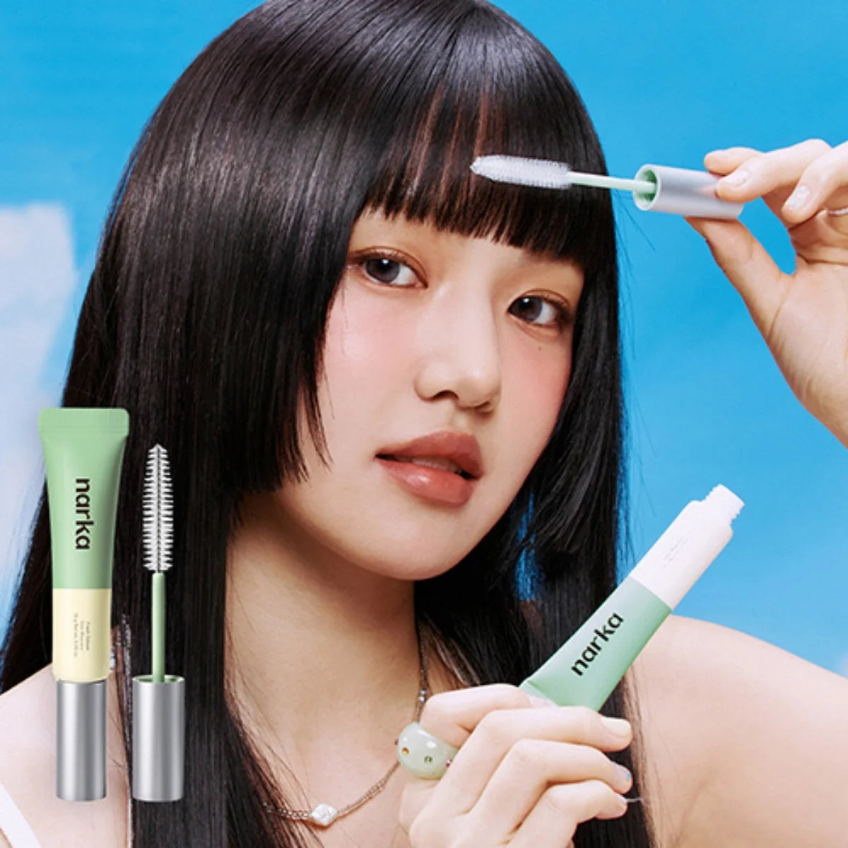 Mint-green hair mascara applicator brush and tube held near straight bangs