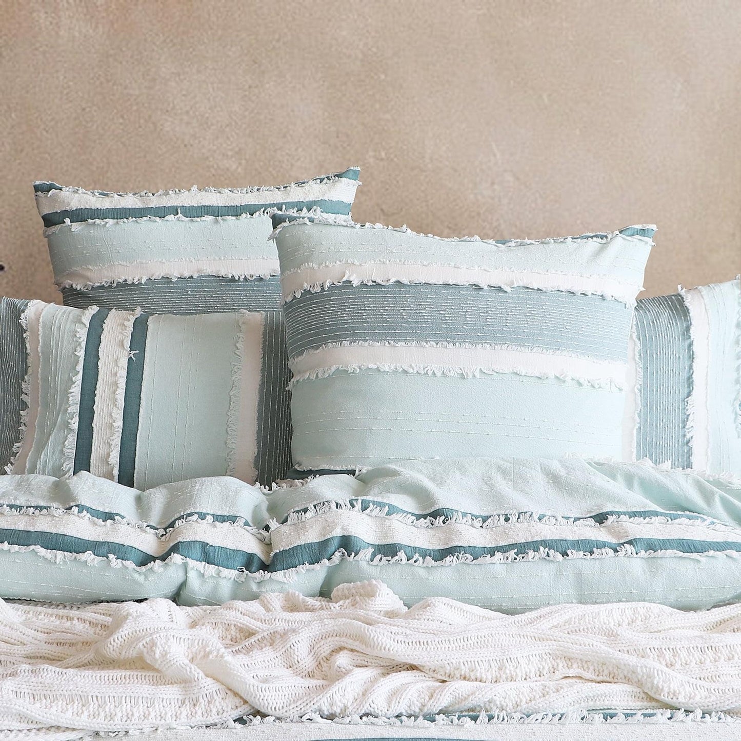 Light blue quilt cover set with white ruffle trim and multiple striped pillowcases