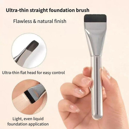 Flat foundation brush with black bristles and clear silver handle, held in hand