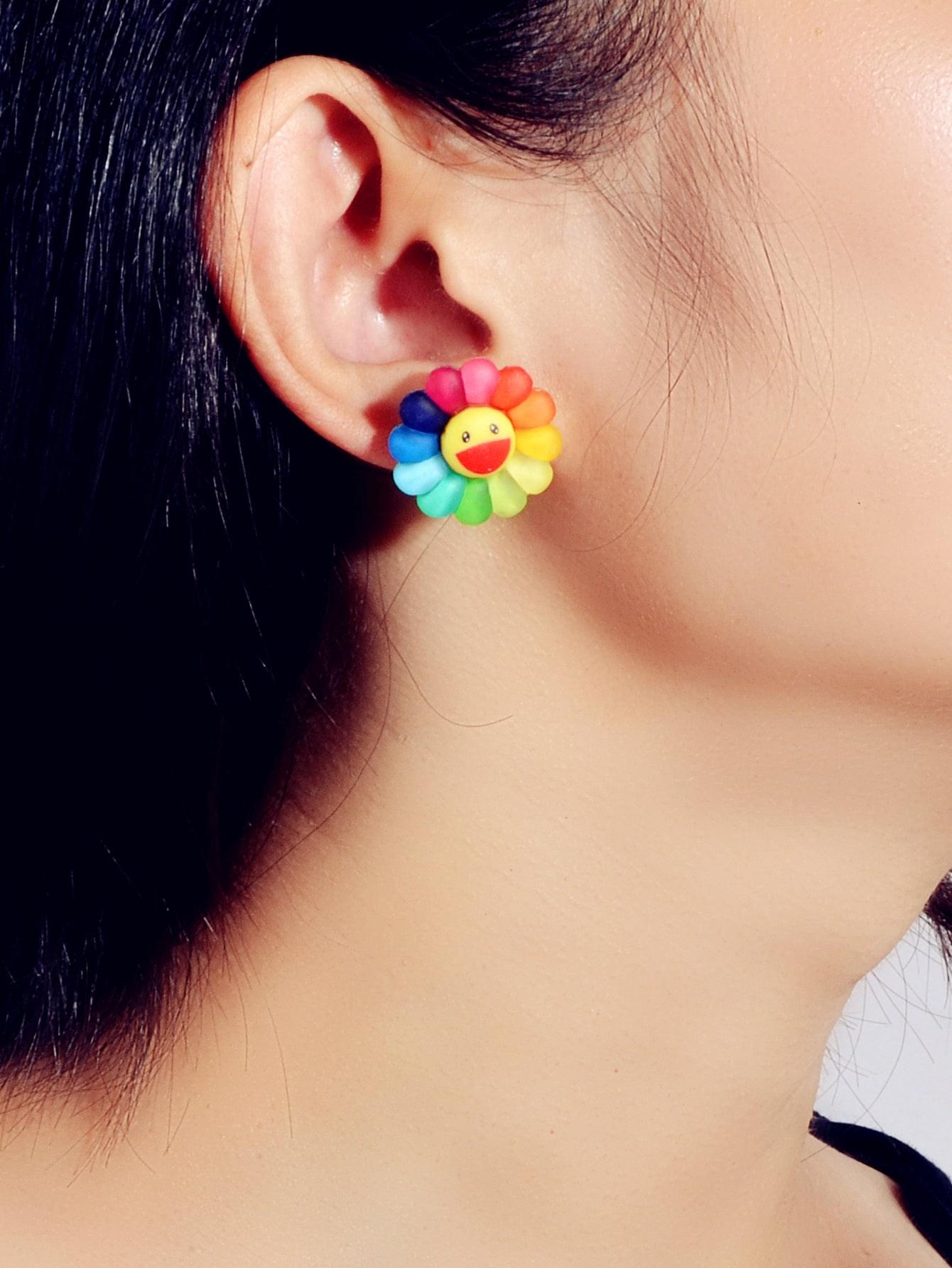 Rainbow flower smile face stud earrings shown on ear, multicolor petals and red face