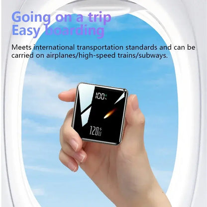 Hand holding a black mini power bank with digital 100% charge display