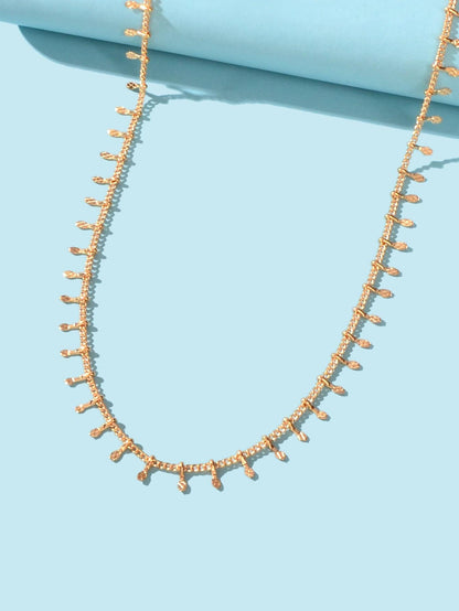 Gold-tone short chain choker necklace with mini dangling charms and oval clasp loops.