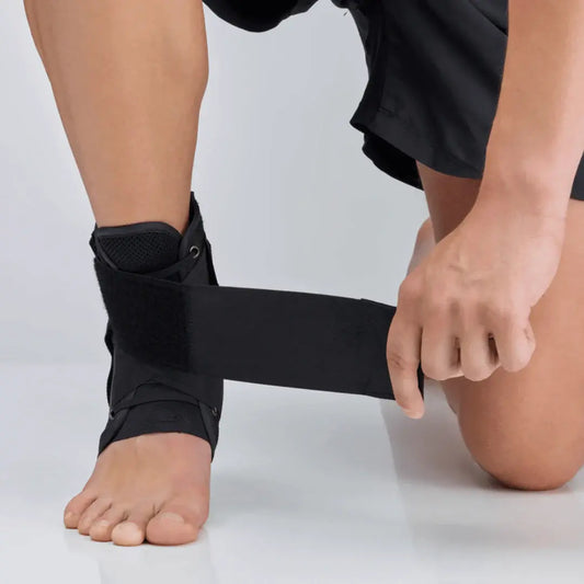 Black ankle brace worn on foot with wide strap and textured mesh support