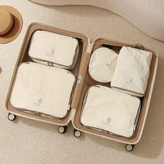 Beige nylon packing cube set with four zippered organizers, laid open