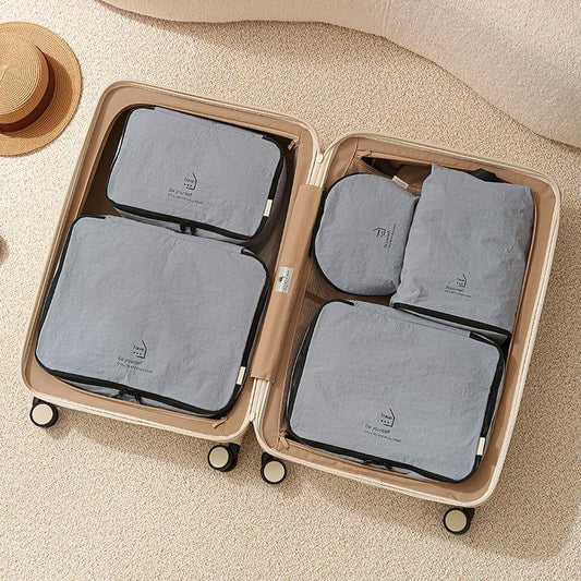 Nylon packing cubes set with zip compartments in light pink, arranged inside a suitcase