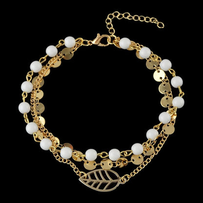 Gold-tone multi-layer anklet with white beads and leaf-shaped charm, chain links