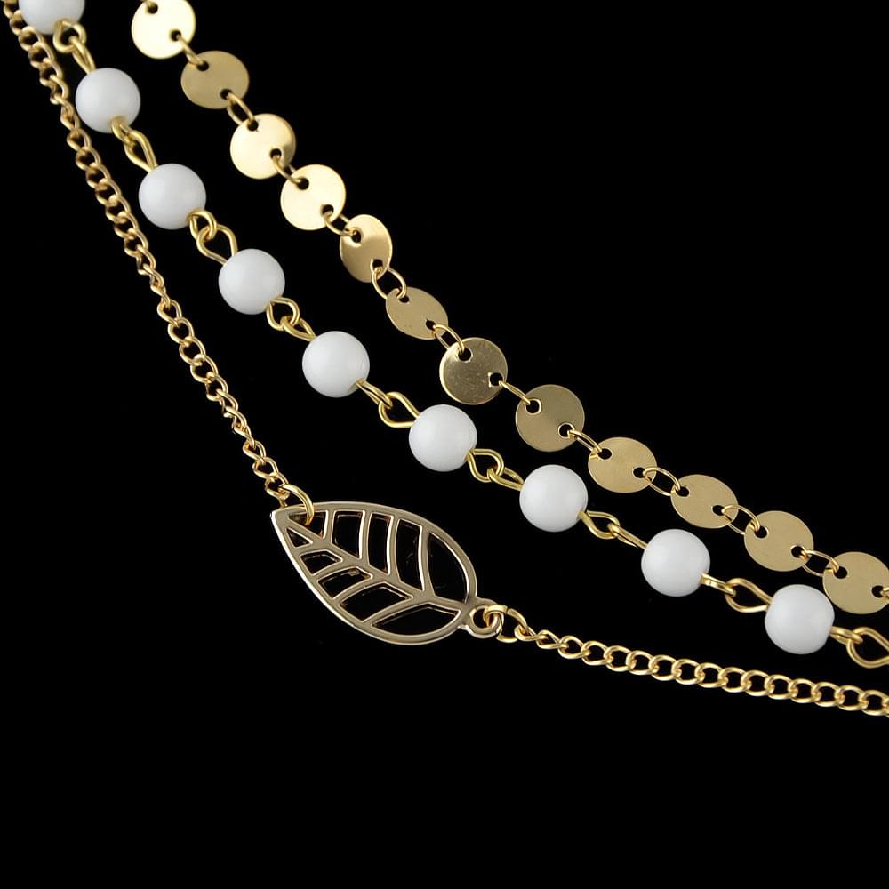 Gold-tone multi-strand anklet with white beads and leaf charm; stacked chain details