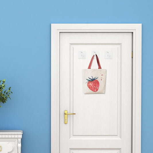 Clear acrylic adhesive wall hooks holding a tote bag near a door