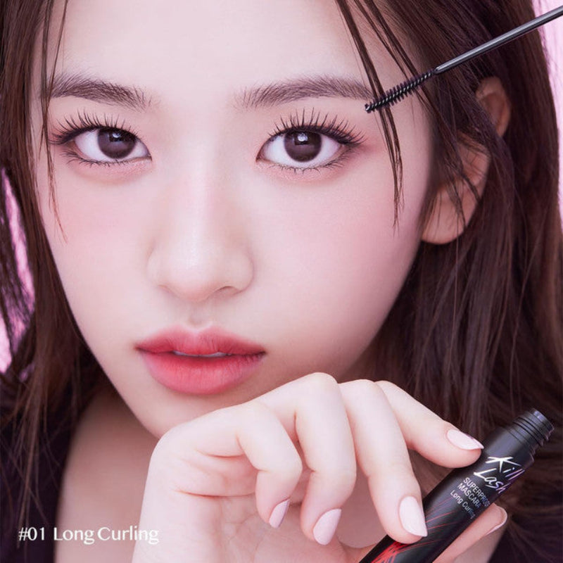 Model holding mascara tube near face with long curled lashes