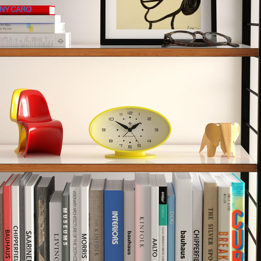 Yellow oval alarm clock with white dial and black hands on its base.