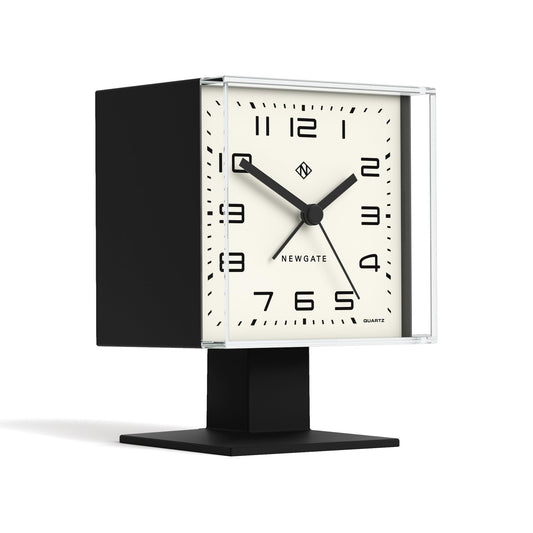 Black alarm clock with clear face and white dial, angled view, black tabletop stand