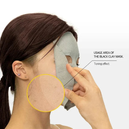 Black clay mask sheet being smoothed on the cheek with fingertips