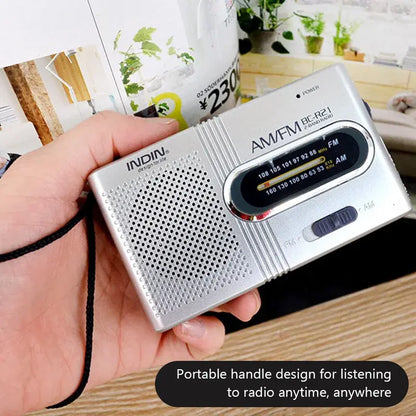 Gray portable AM/FM radio held in hand, speaker grille and black tuning window visible.